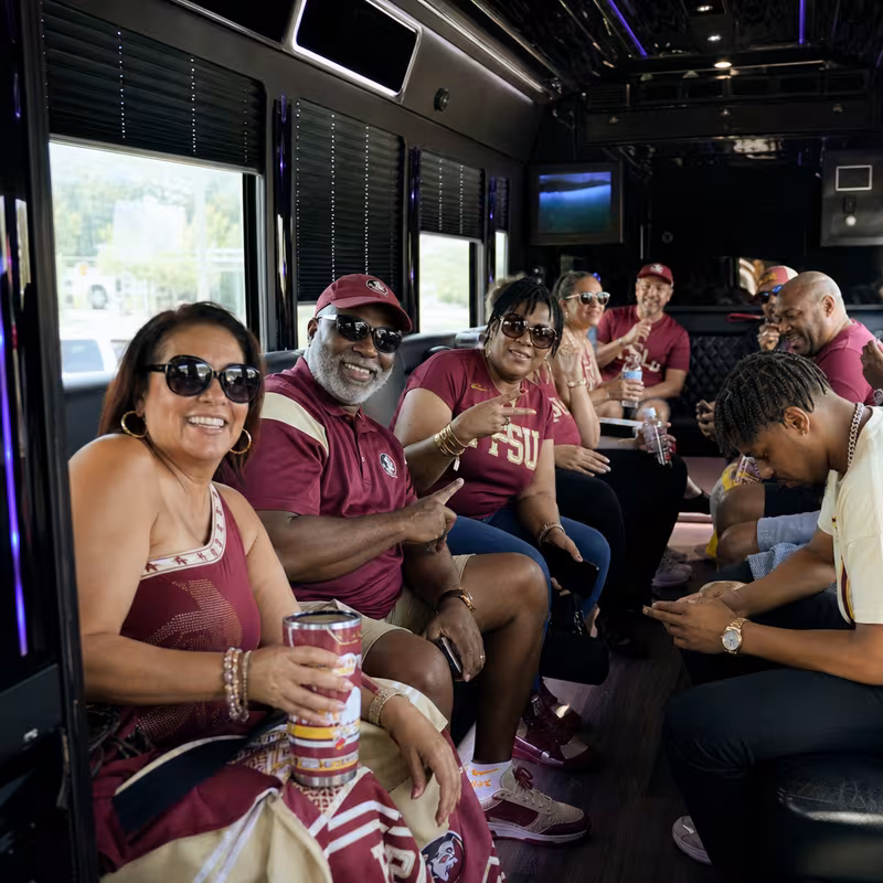 Group boarding a white charter bus for Sporting Event Transportation transportation in Tallahassee